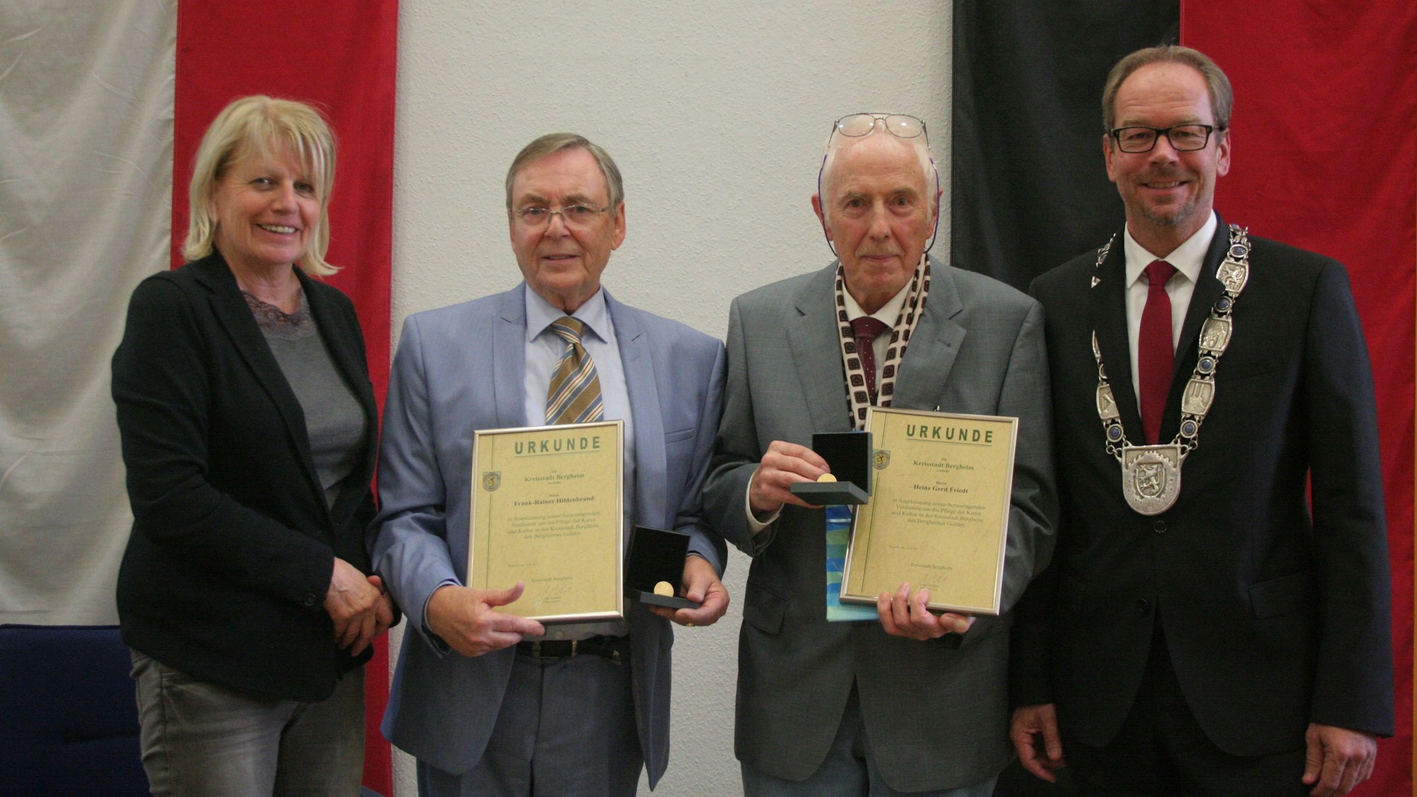 Auf dem Bild sind eine Frau und drei Männer bei einer Ehrung in feierlichem Rahmen zu sehen.