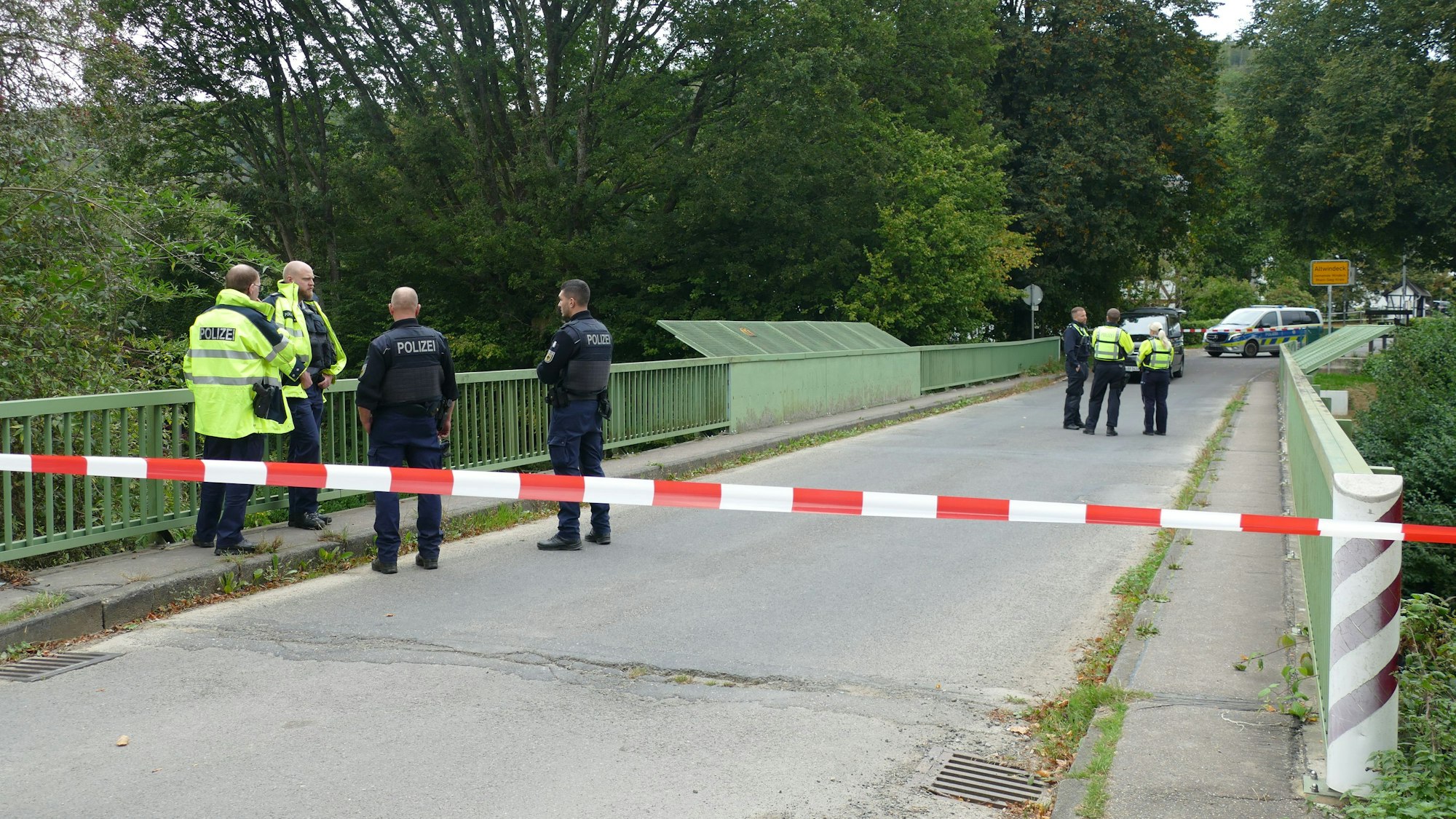 Polizeiabsperrband an einer Brücke, dahinter Beamte.