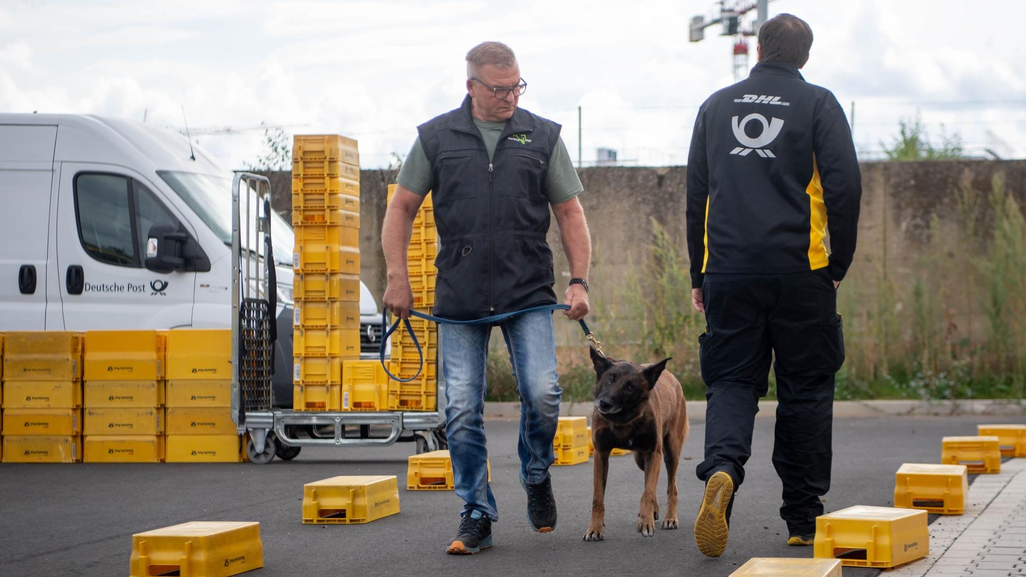 Ein Zusteller geht an Uwe Graute vorbei, der den Schäferhund an der Leine führt.
