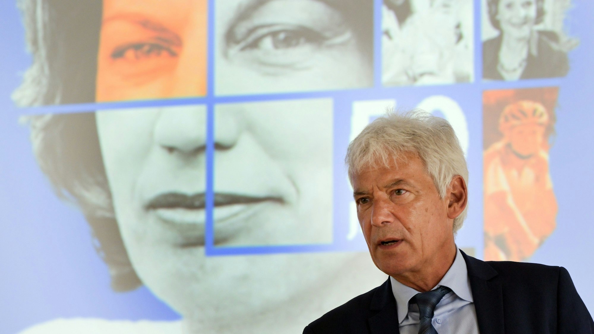 Gerd Nettekoven, Vorstandsvorsitzender der Deutschen Krebshilfe, steht vor einem Bild von Mildred Scheel.