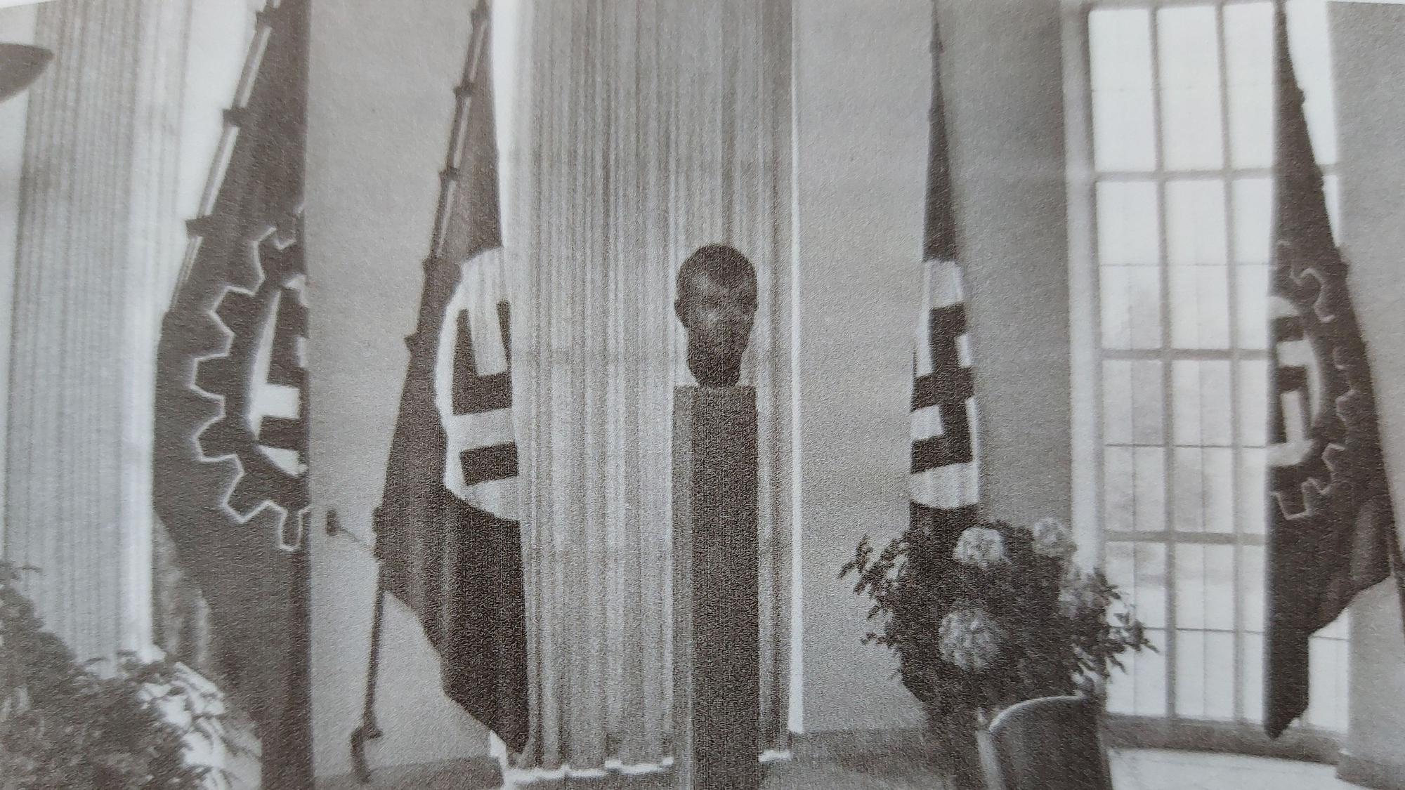 Historisches Foto: Ein Raum mit Hitler-Büste und Hakenkreuz-Fahnen.