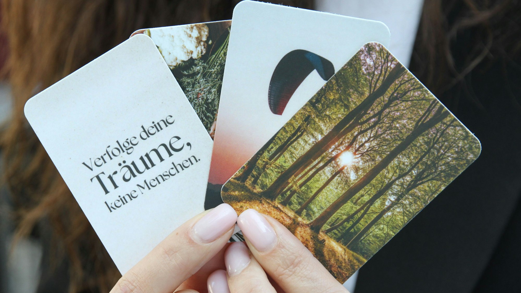 Eine Hand hält vier Motivkarten.