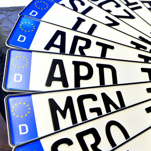 Verschiedene Autokennzeichen liegen aufgefächert übereinander.