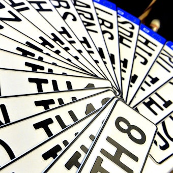 Verschiedene Autokennzeichen liegen aufgefächert übereinander.