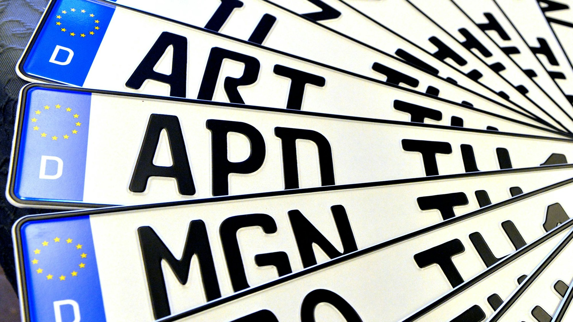 Verschiedene Autokennzeichen liegen aufgefächert übereinander.