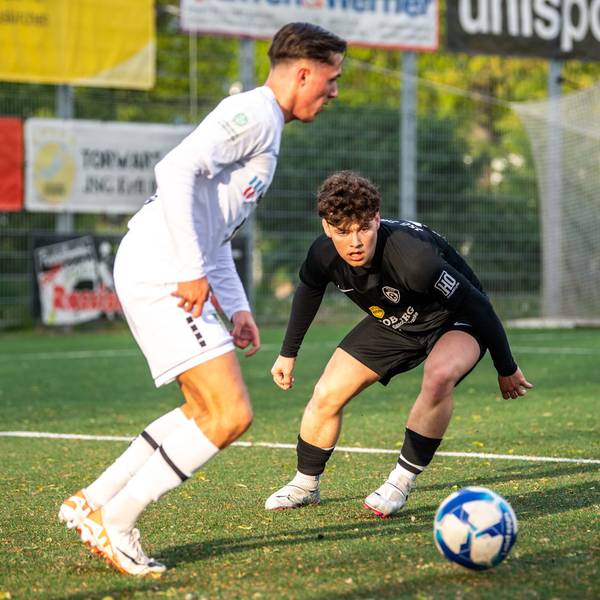 Ein Fußballspieler schaut gebannt auf einen Ball, der von einem Gegenspieler geführt wird.