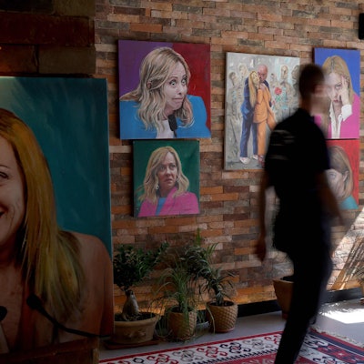 Ein Gast geht am 23. September 2024 an Porträts der italienischen Ministerpräsidentin Giorgia Meloni vorbei, die die Wand des Restaurants „Trattoria Meloni“ in Shengjin, etwa 60 km nordwestlich von Tirana, zieren.