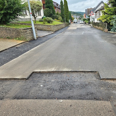 Das Foto zeigt geflickte Stellen, die letzte Teerschicht fehlt.
