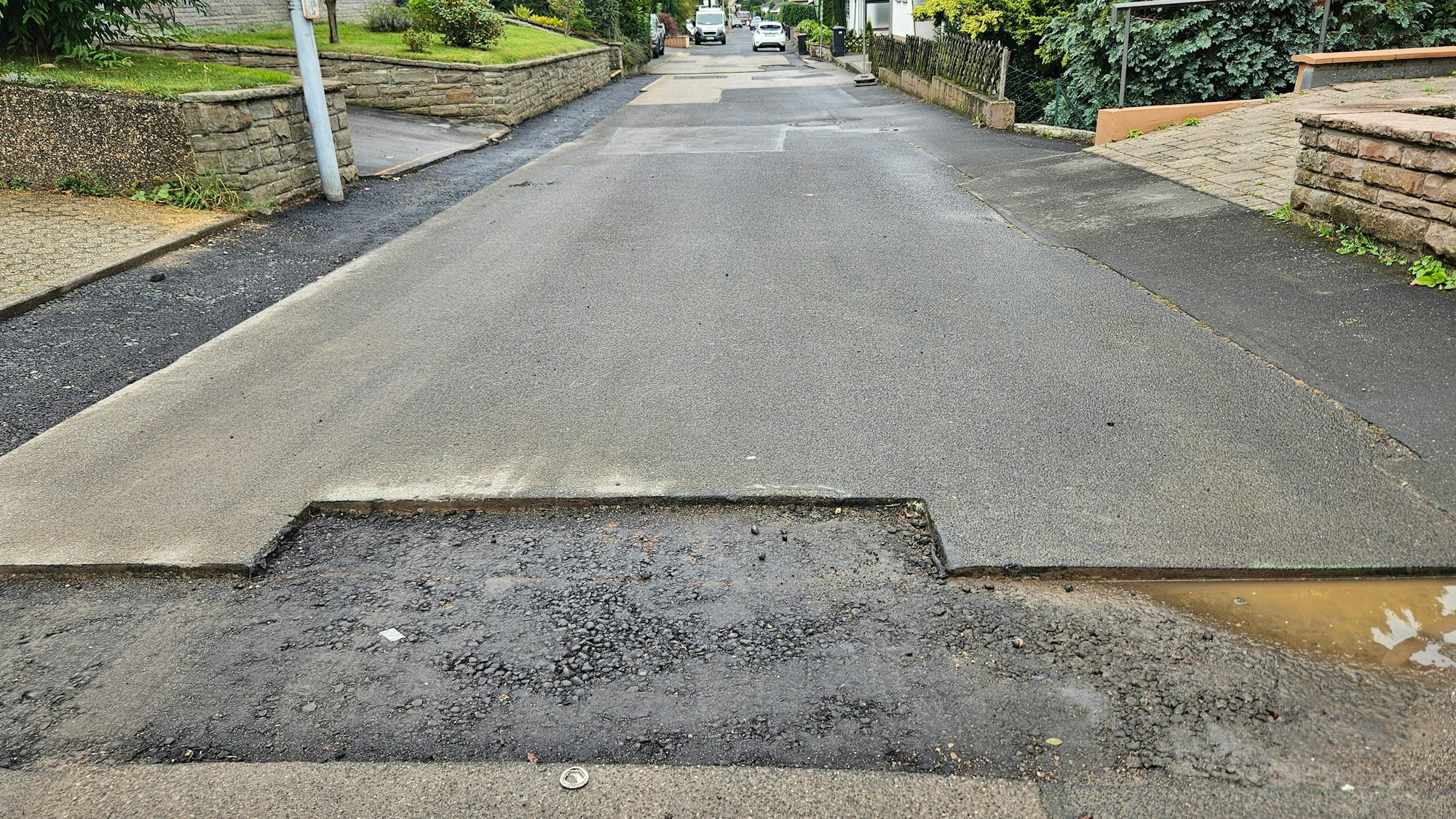 Das Foto zeigt geflickte Stellen, die letzte Teerschicht fehlt.