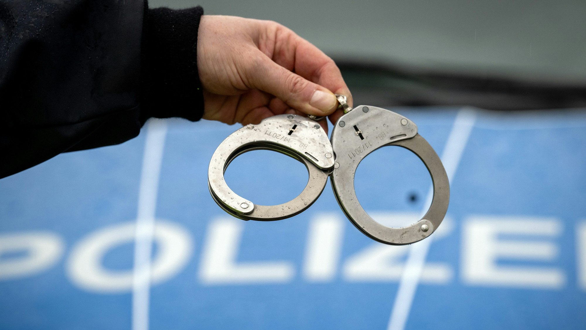 Ein Polizist hält ein Paar Handschellen.