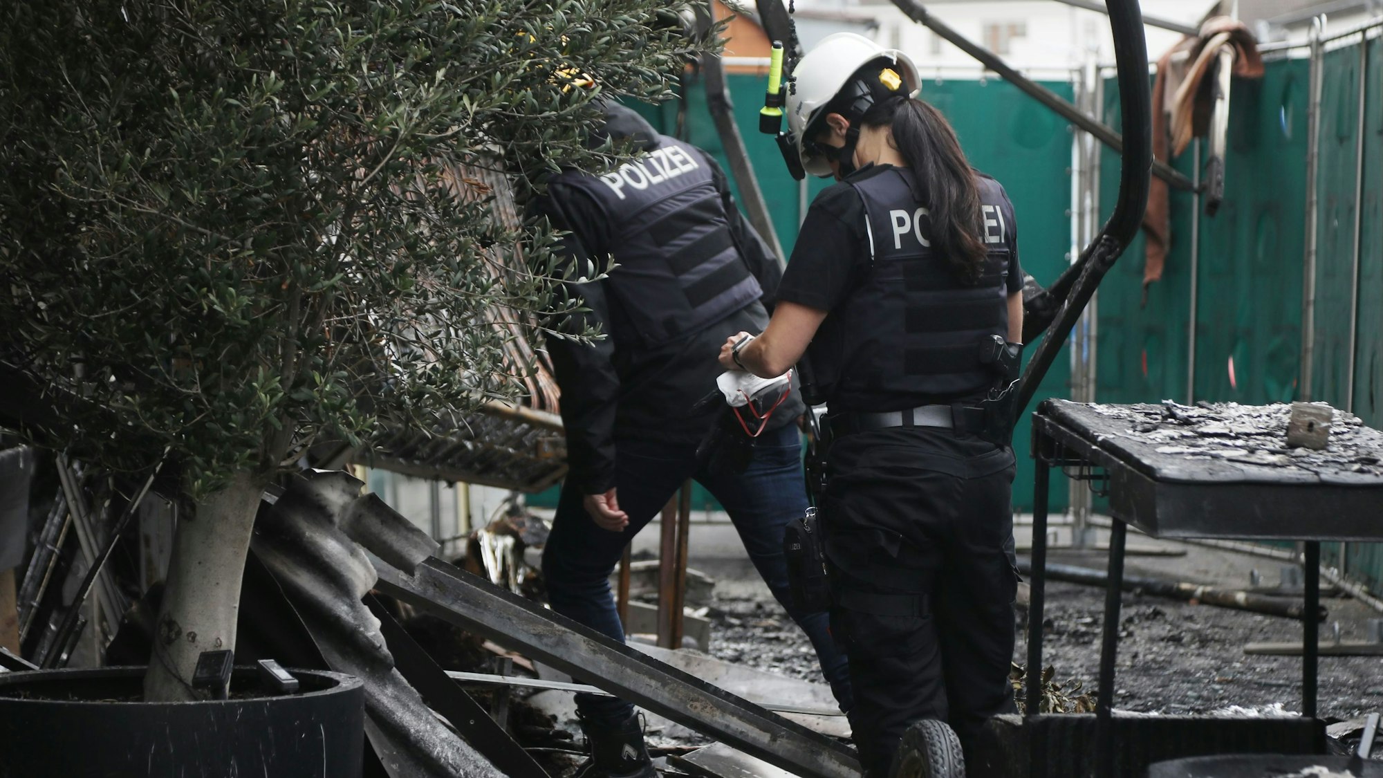 Polizisten auf Spurensuche in dem ausgebrannten Café an der Escher Straße.