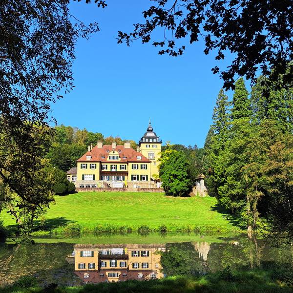 Schlosshotel Lerbach ist hinter dem Schlossteich zwischen Bäumen zu sehen.