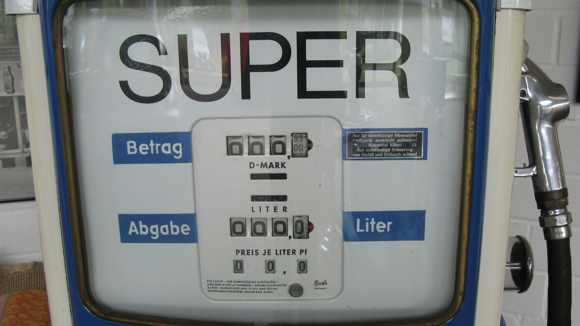 Das Sichtfenster einer alten Tankstellen-Zapfsäule mit D-Mark-Preisanzeige und Literanzeige und der Zapfpistole daneben.