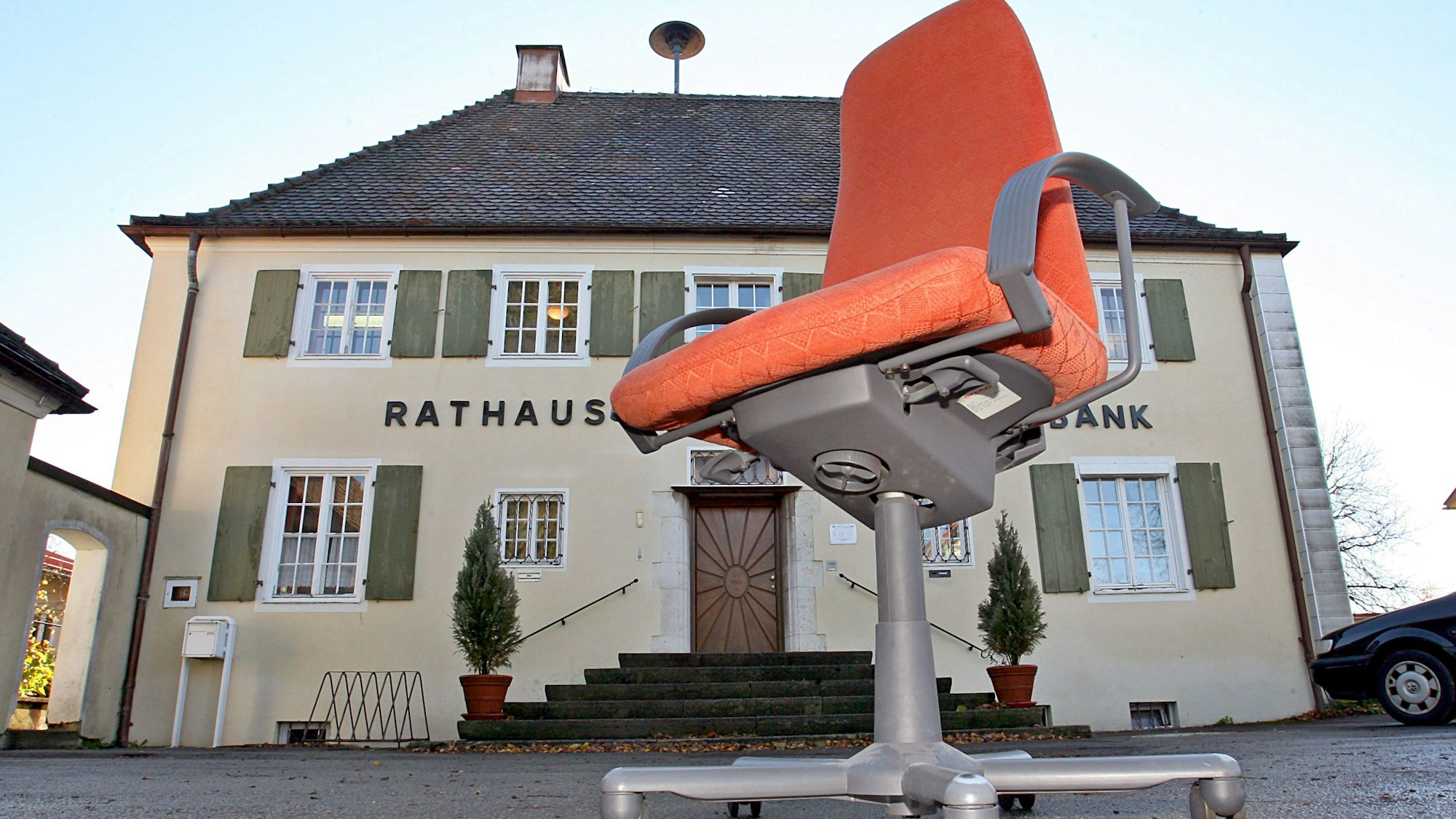 Ein Rathaus, davor ein Bürostuhl auf Rollen.