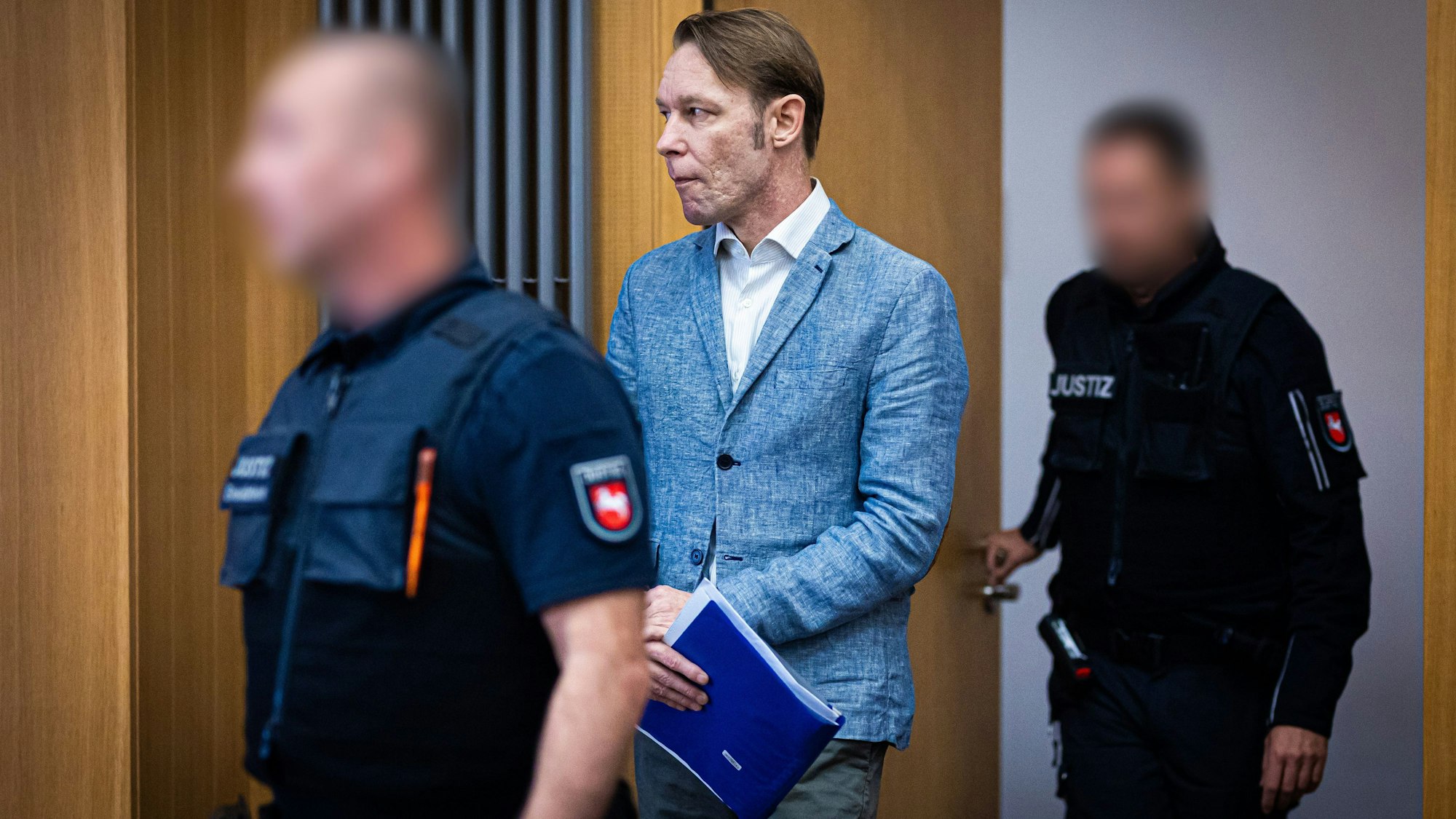 Der Angeklagte Christian B. (M) wird von Justizmitarbeitern in einen Gerichtssaal im Landgericht geführt.