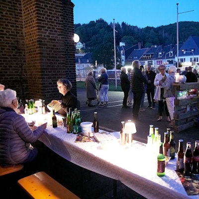 Menschen stehen miteinander im Gespräch vor der Kirche oder sitzen an Biertischen.