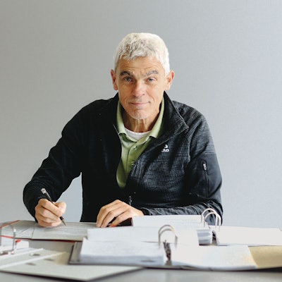 Ein grauhaariger Mann sitzt an vielen Akten.