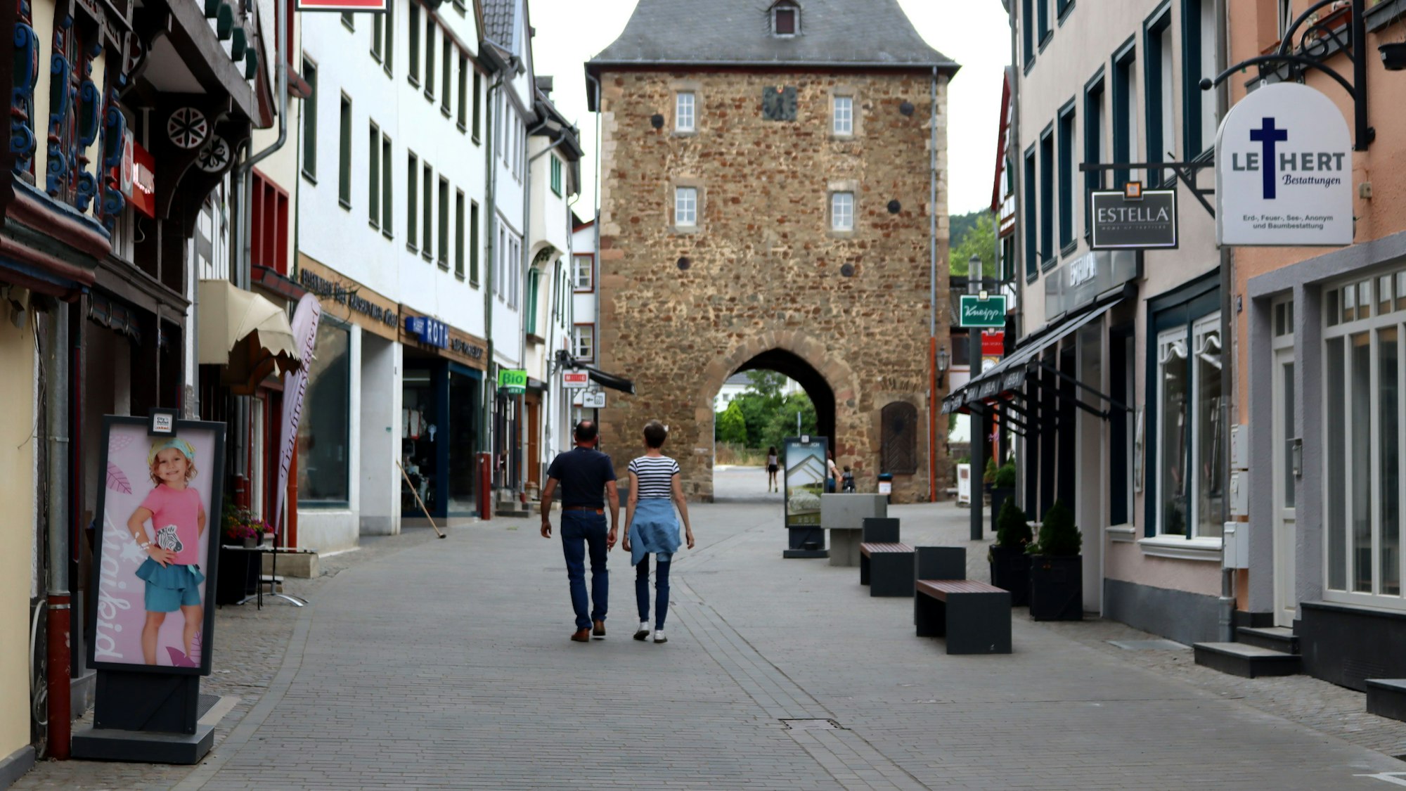 Zwei Menschen gehen nebeneinander durch die Orchheimer Straße in Bad Münstereifel in Richtung Orchheimer Tor.