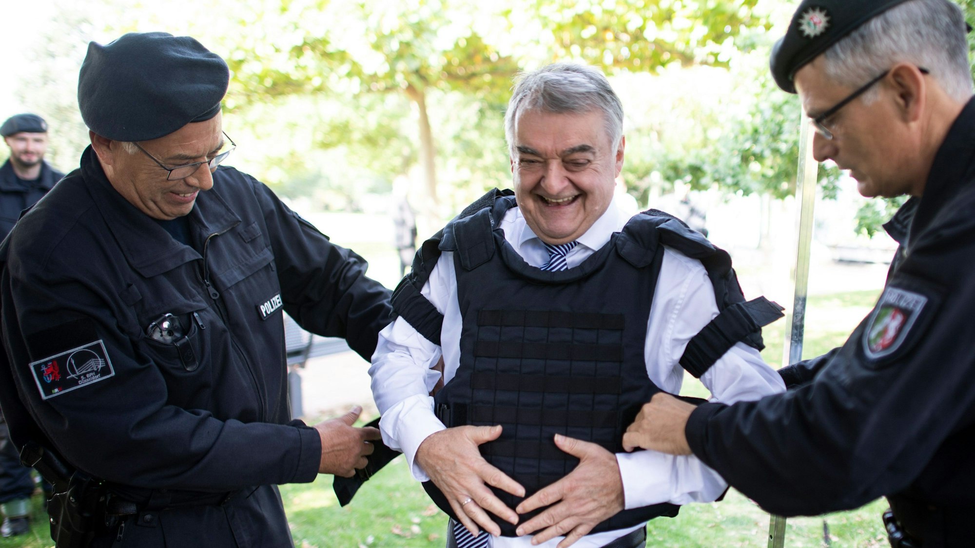 Polizisten legten Herbert Reul (CDU, M) bei der Vorstellung der neuen Köperschutzausstattung eine Schutzweste an.