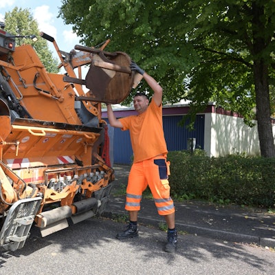 Das Foto zeigt einen Mitarbeiter der Müllabfuhr bei der Arbeit