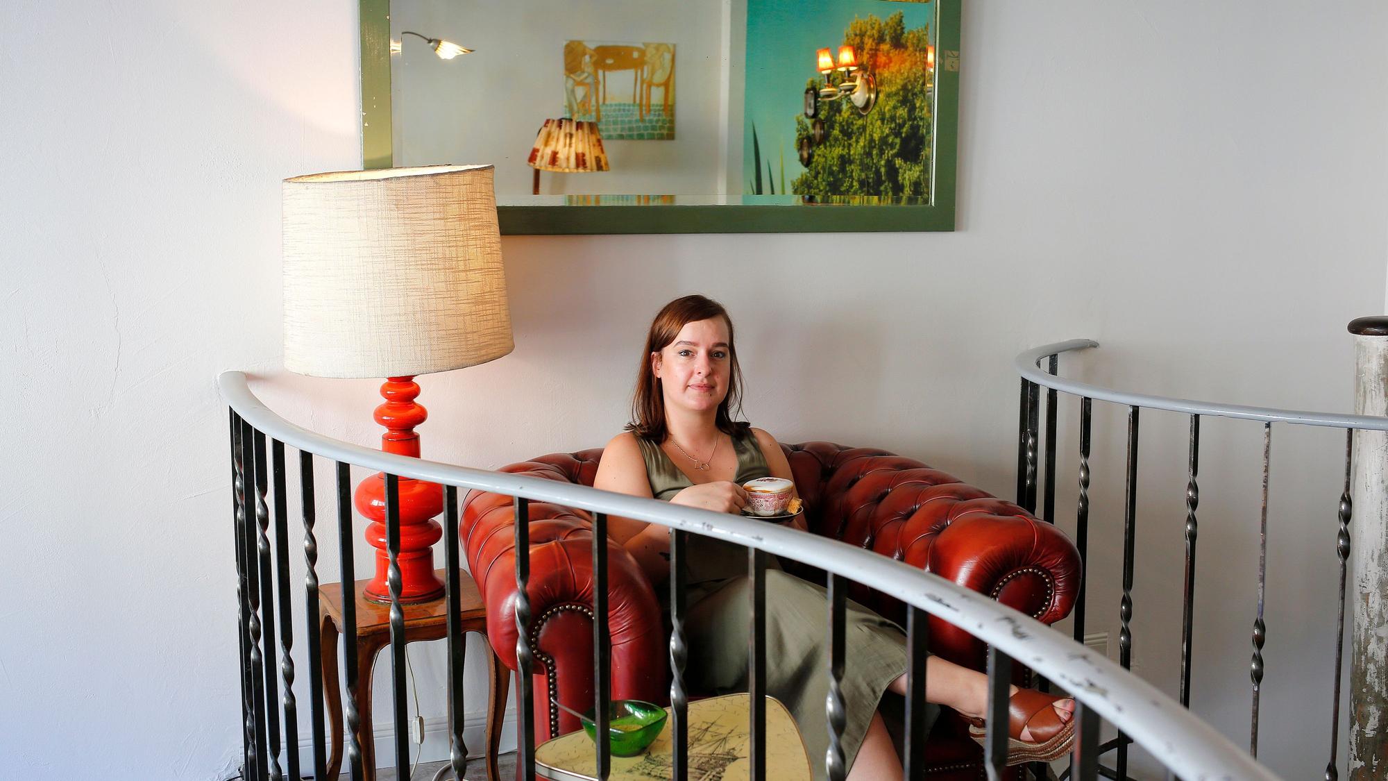 Eine Frau sitzt in einem Sessel im Cafe Leuchte in Köln.