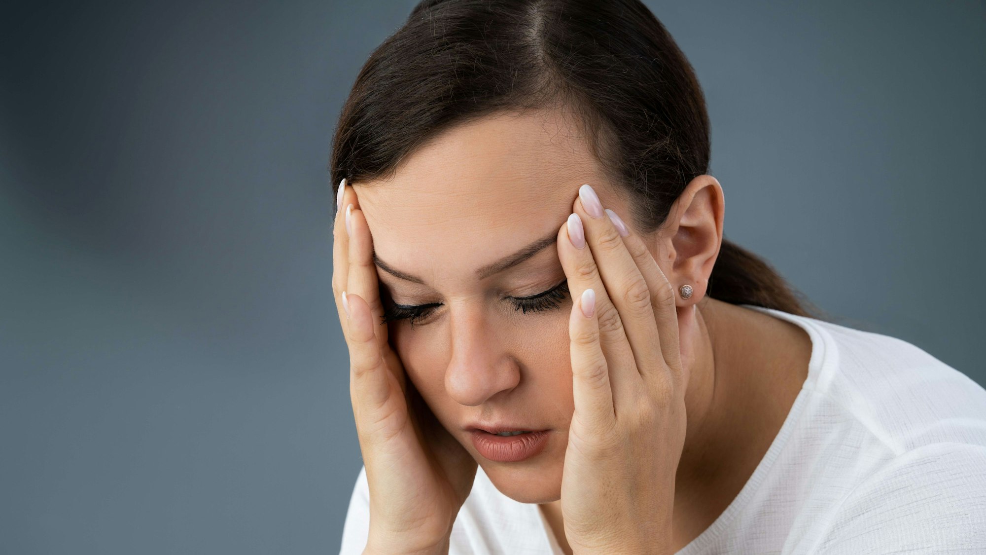 Eine Frau greift mit den Händen an den Kopf