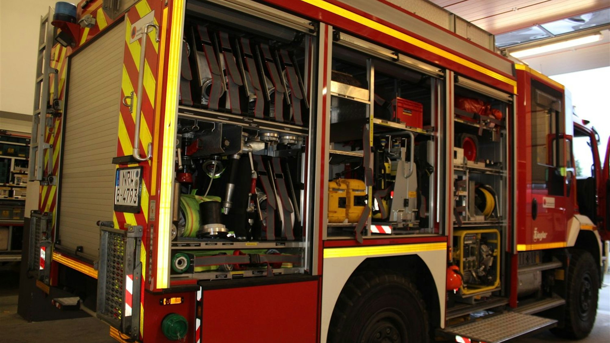 Ein Rüstwagen der Löschgruppe Heiligenhaus der Freiwilligen Feuerwehr in der Stadt Overath steht mit offenen Rolltüren in der Fahrzeughalle.