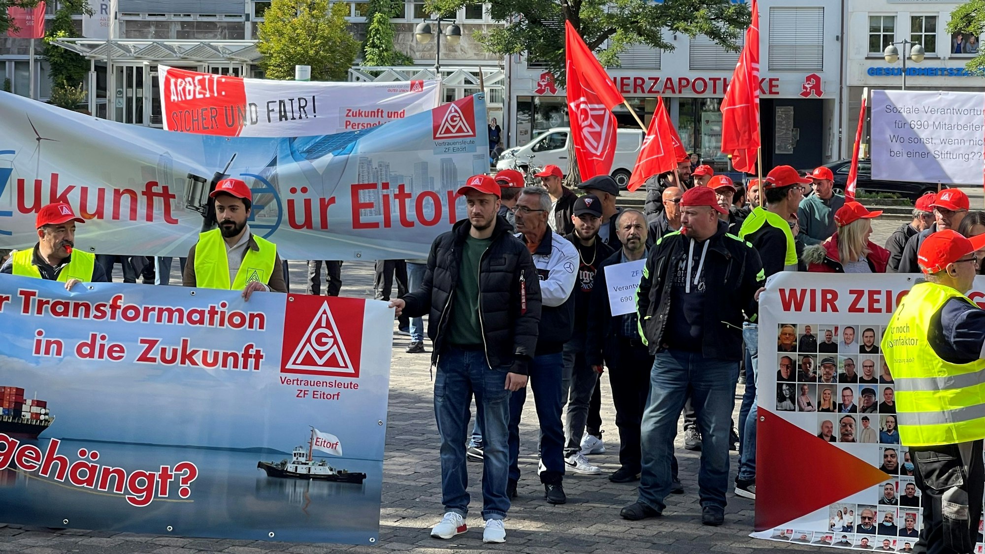 Demonstration von Menschen mit Plakaten, Kappen und Fahnen.