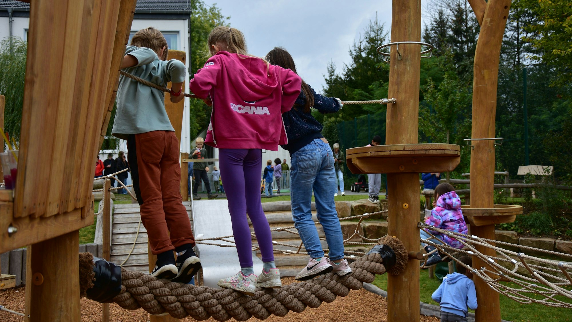 Drei Kinder balancieren auf einem dicken Seil.