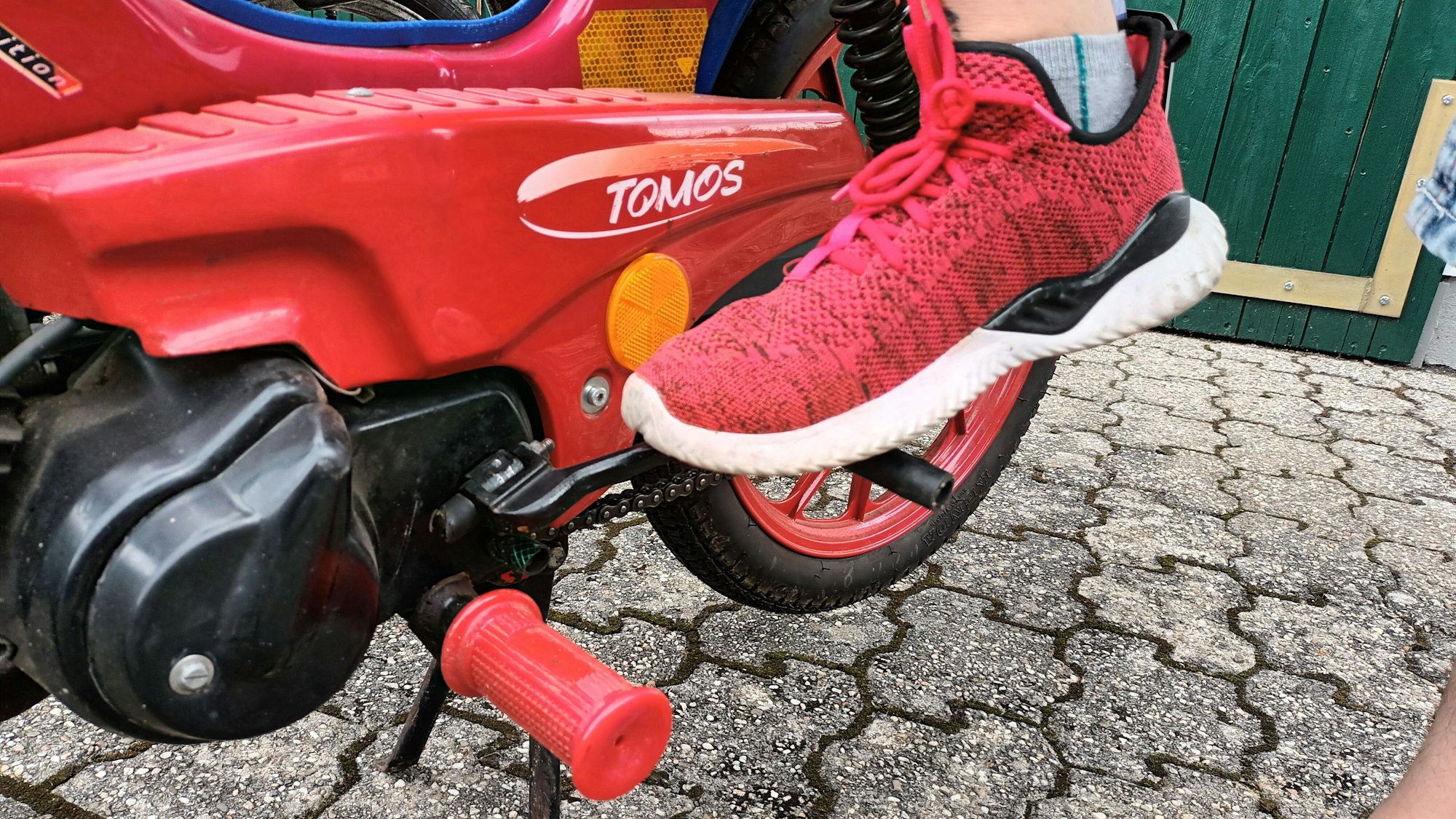 Ein Mann tritt einen Hebel an einem Moped heruntert