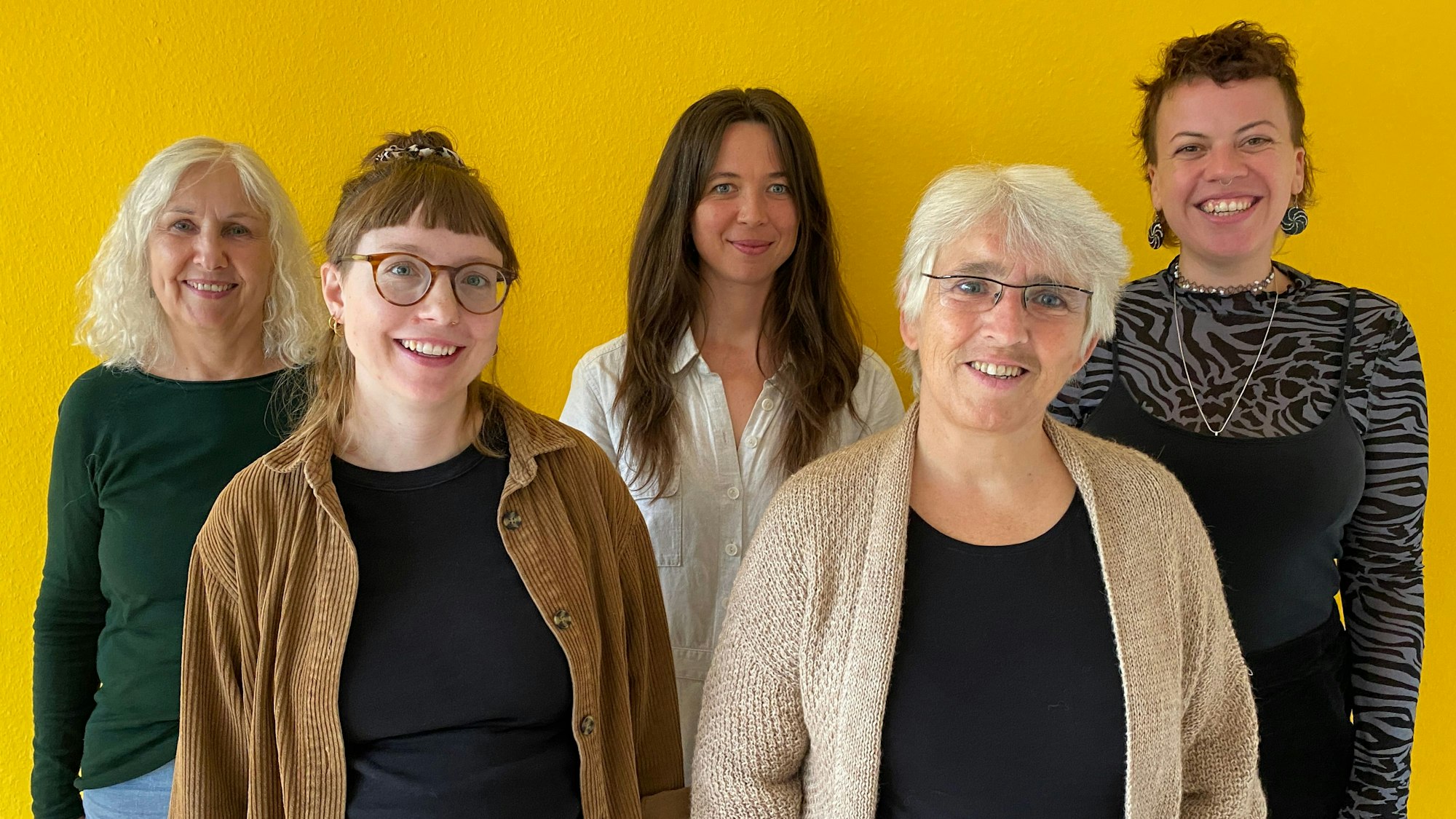 Fünf Frauen stehen vor einer gelben Wand.