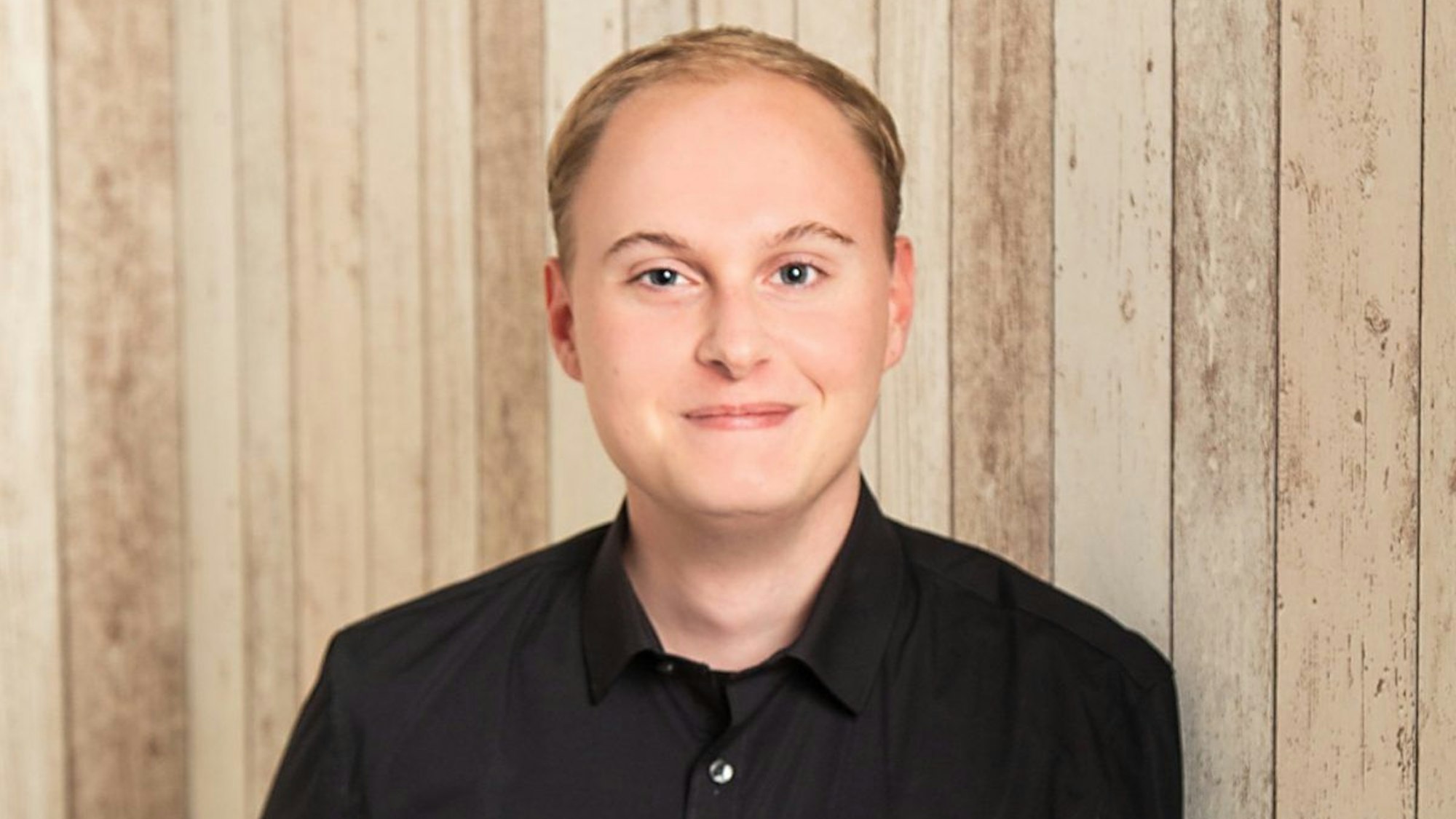 Auf dem Foto ist ein junger Mann in einem schwarzen Hemd zu sehen.