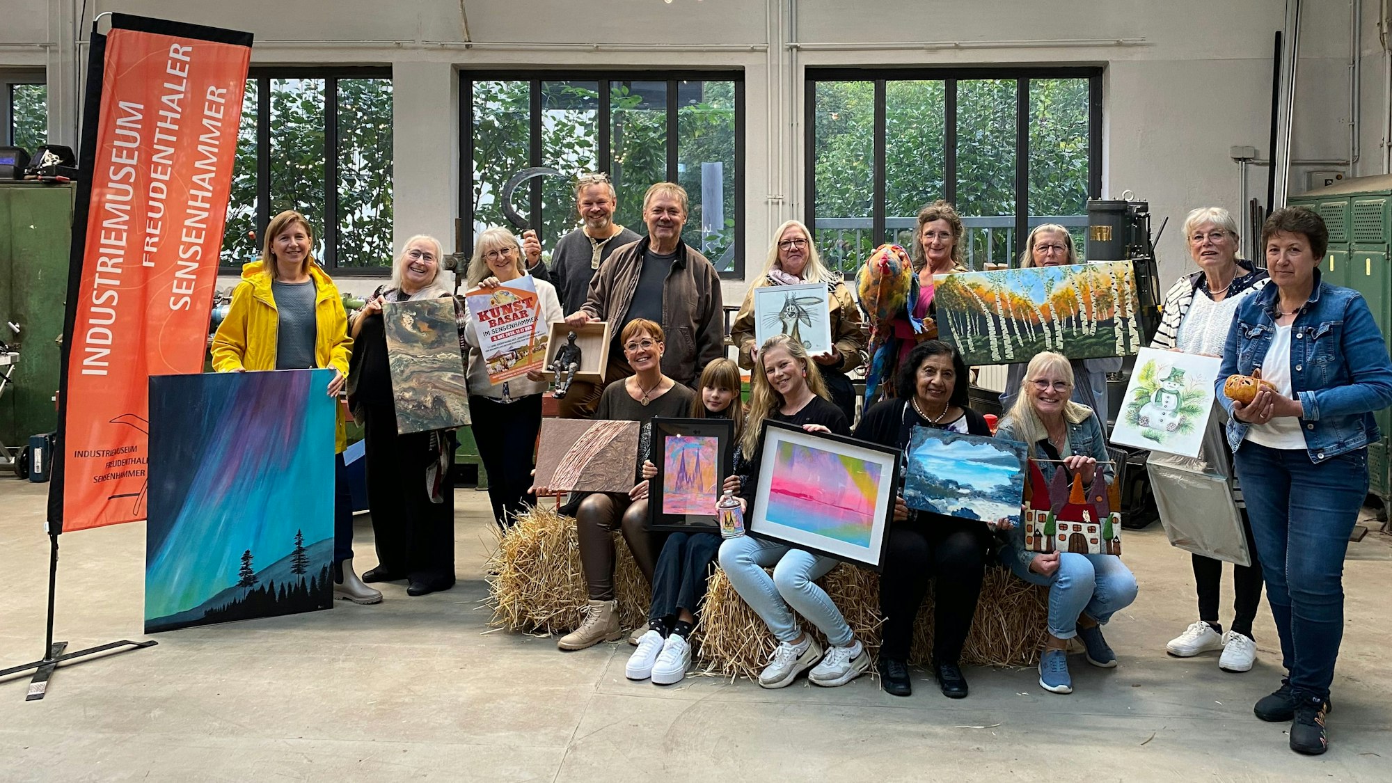 Menschen stehen in einer Halle und halten Bilder hoch.