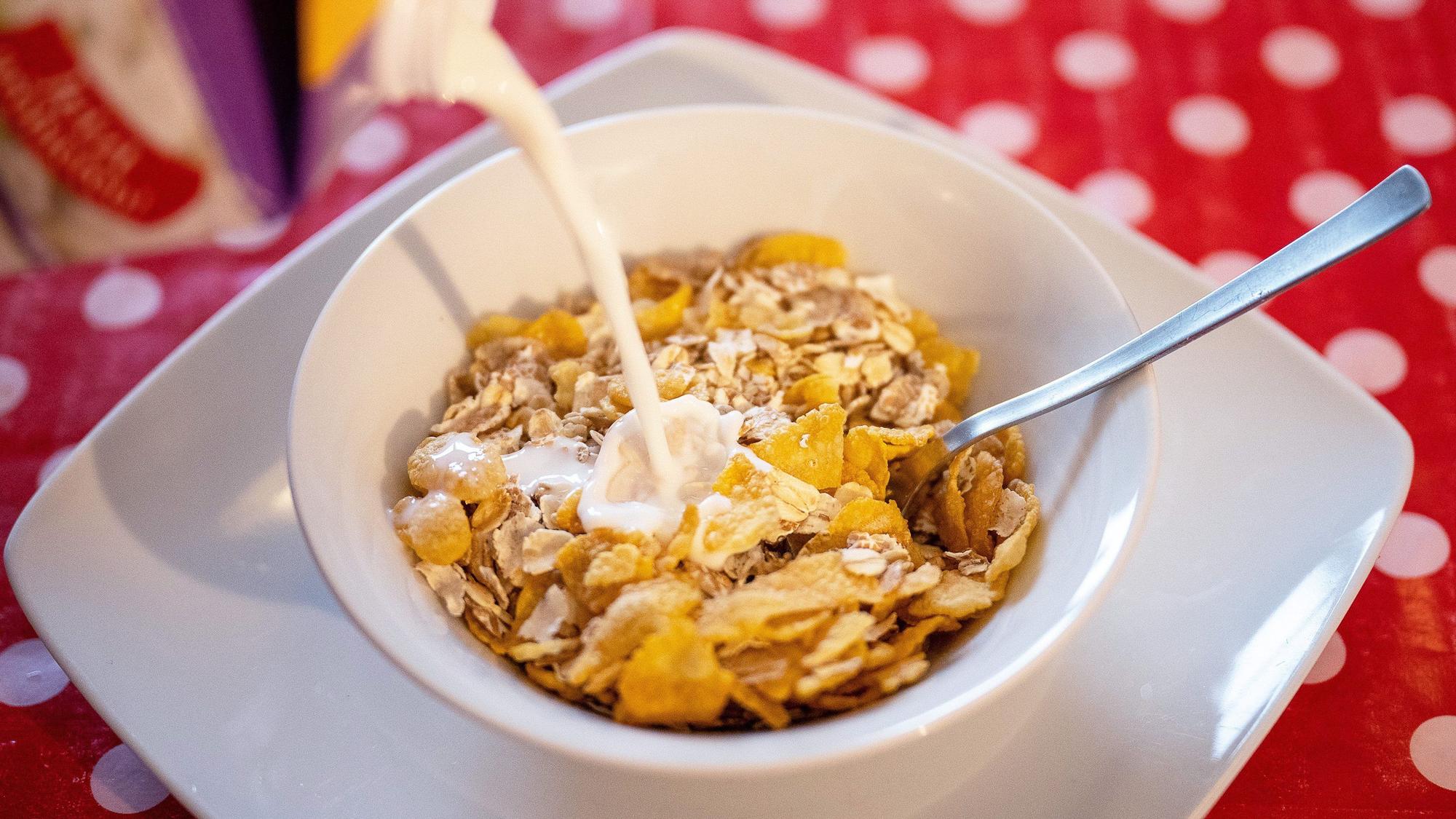 Das Bild zeigt eine Schale mit Müsli, in die Milch gegossen wird.