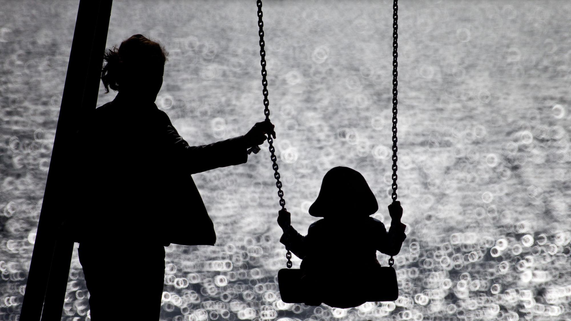 ARCHIV - 16.09.2013, Hamburg: Eine Mutter schaukelt ihr Kind auf einem kleinen Spielplatz am glitzernden Wasser der Alster. (zu dpa: «Anteil Alleinerziehender etwas gesunken - Überwiegend Frauen») Foto: Christian Charisius/dpa +++ dpa-Bildfunk +++