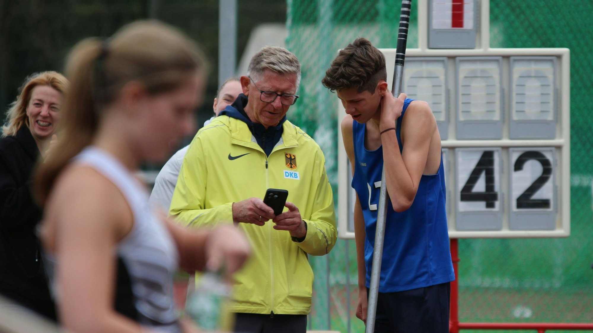Bei einem Wettkampf gucken Leszek Klima und sein Athlet gemeinsam aufs Handy, sie analysieren den Sprung.