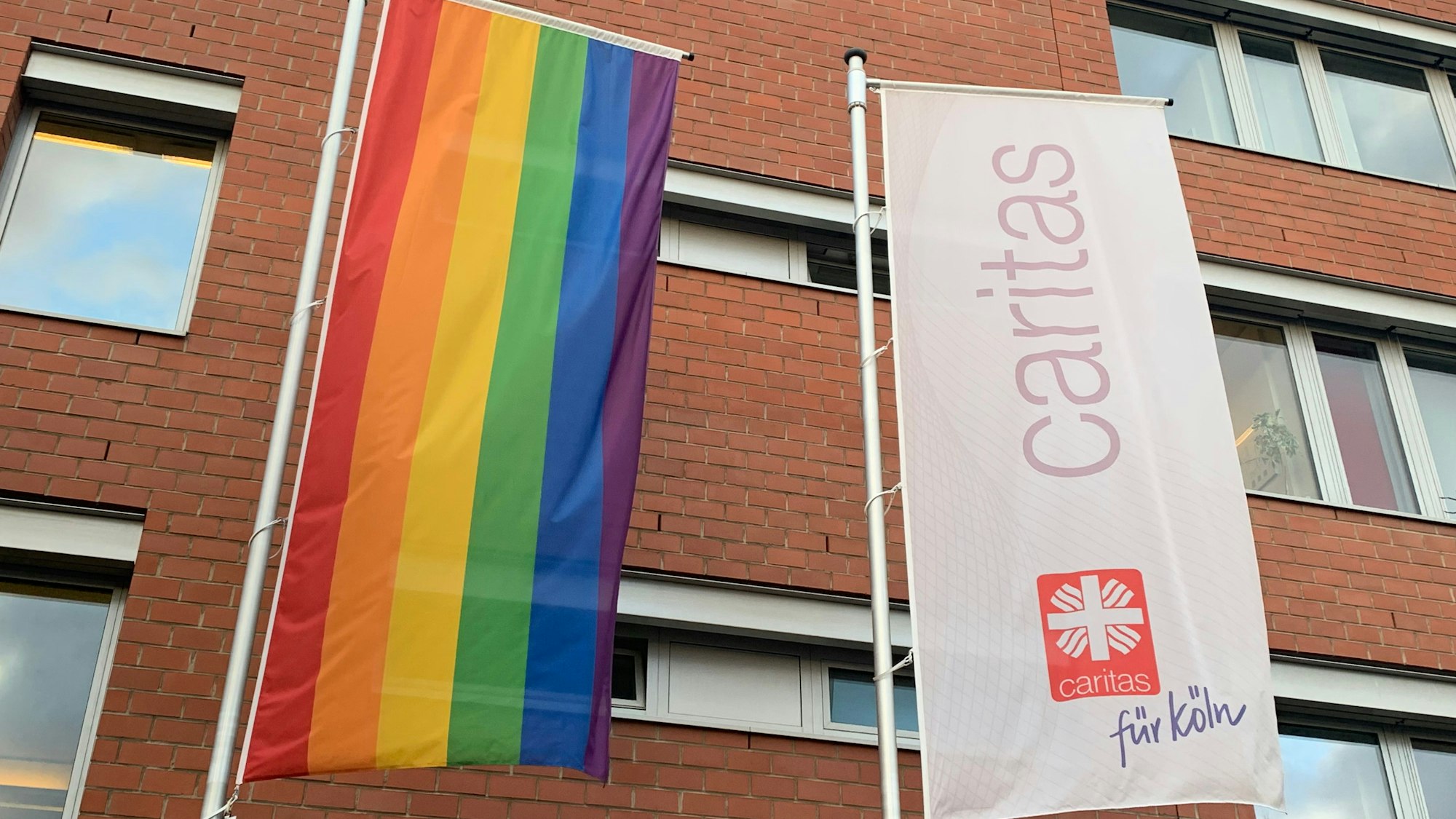 Flagge der Caritas und Pride-Flagge vor der Geschäftsstelle Köln.