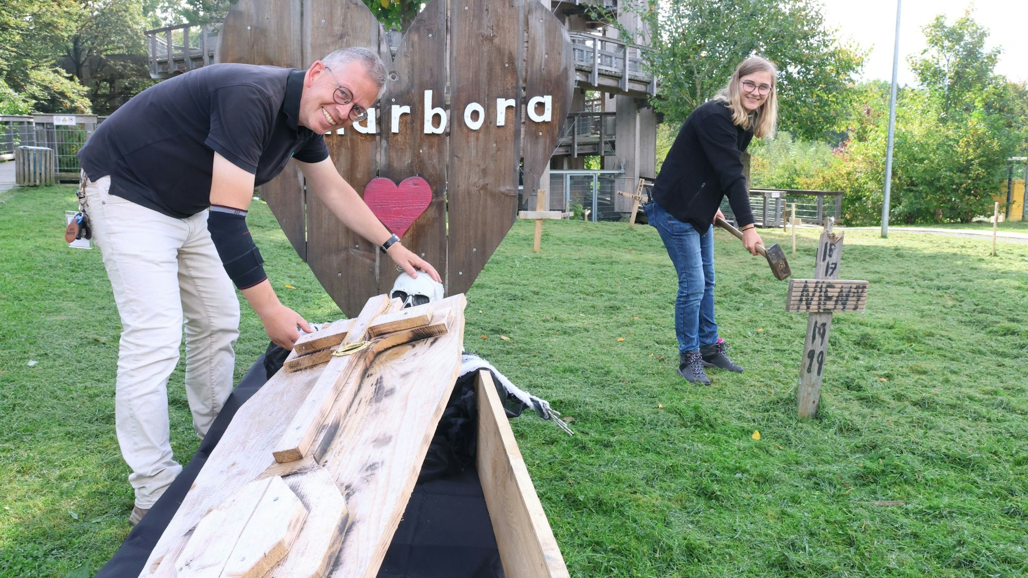 In einen Gruselpark verwandeln Patrick Mielke und Ulrike Schmoock das Gelände von Panarbora in Waldbröl. Er steht an einem Sarg mit Skelett. Sie haut ein Holzkreuz in die Erde.
