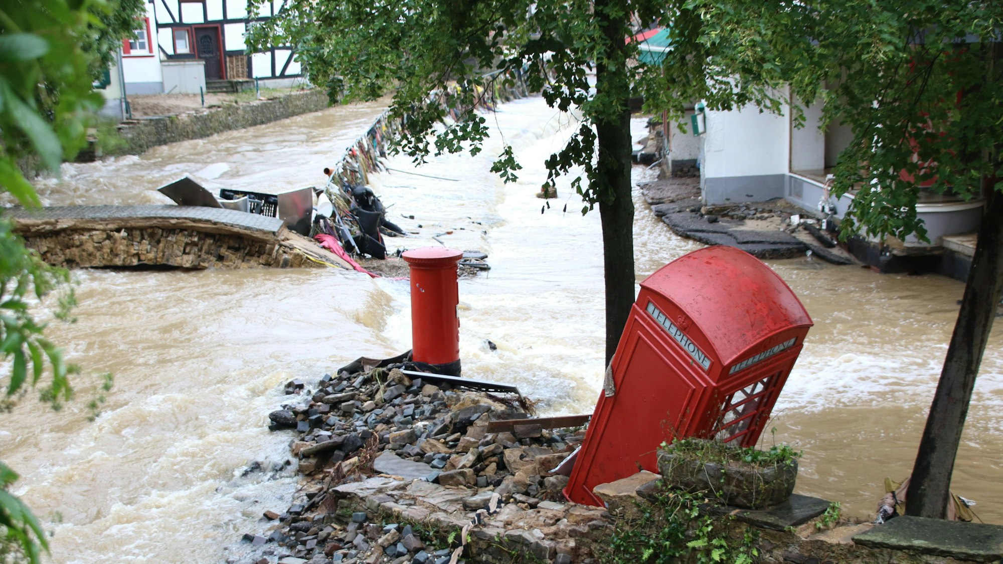 Archivfoto der Redaktion, dass die reißende Erft und die an einem Baum gestrandete Telefonzelle zeigt.