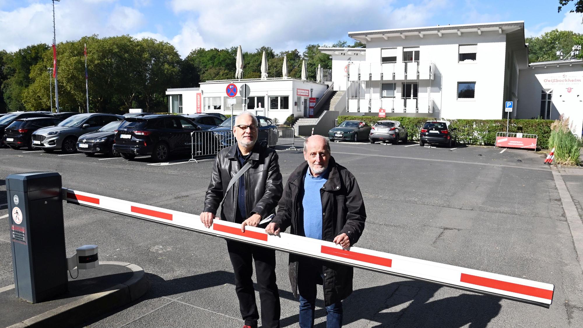 Die beiden Männer stehen auf dem Parkplatz des Geißbockheims.