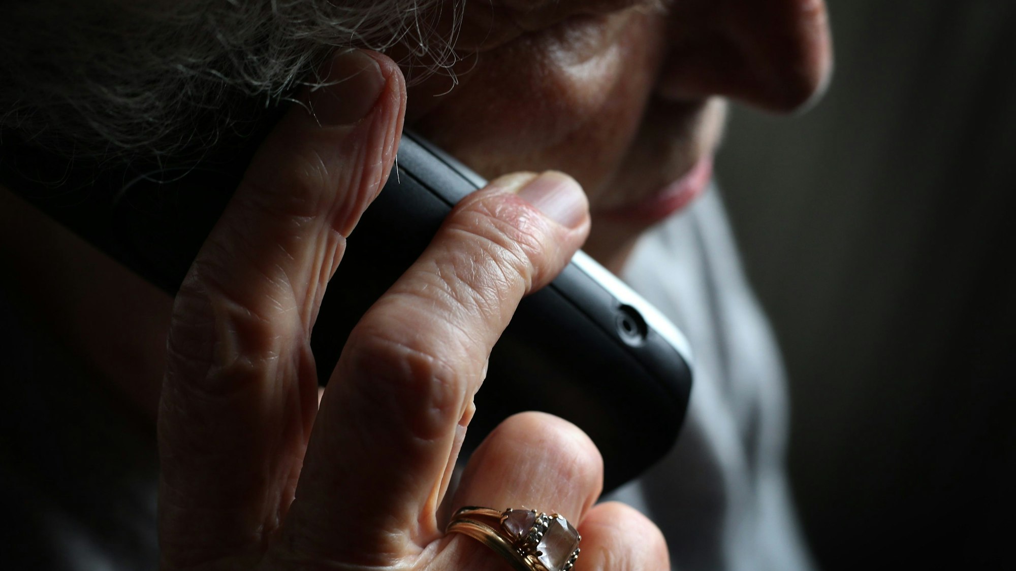 Das Bild zeigt eine ältere Frau, die einen Telefonhörer in der Hand hält.