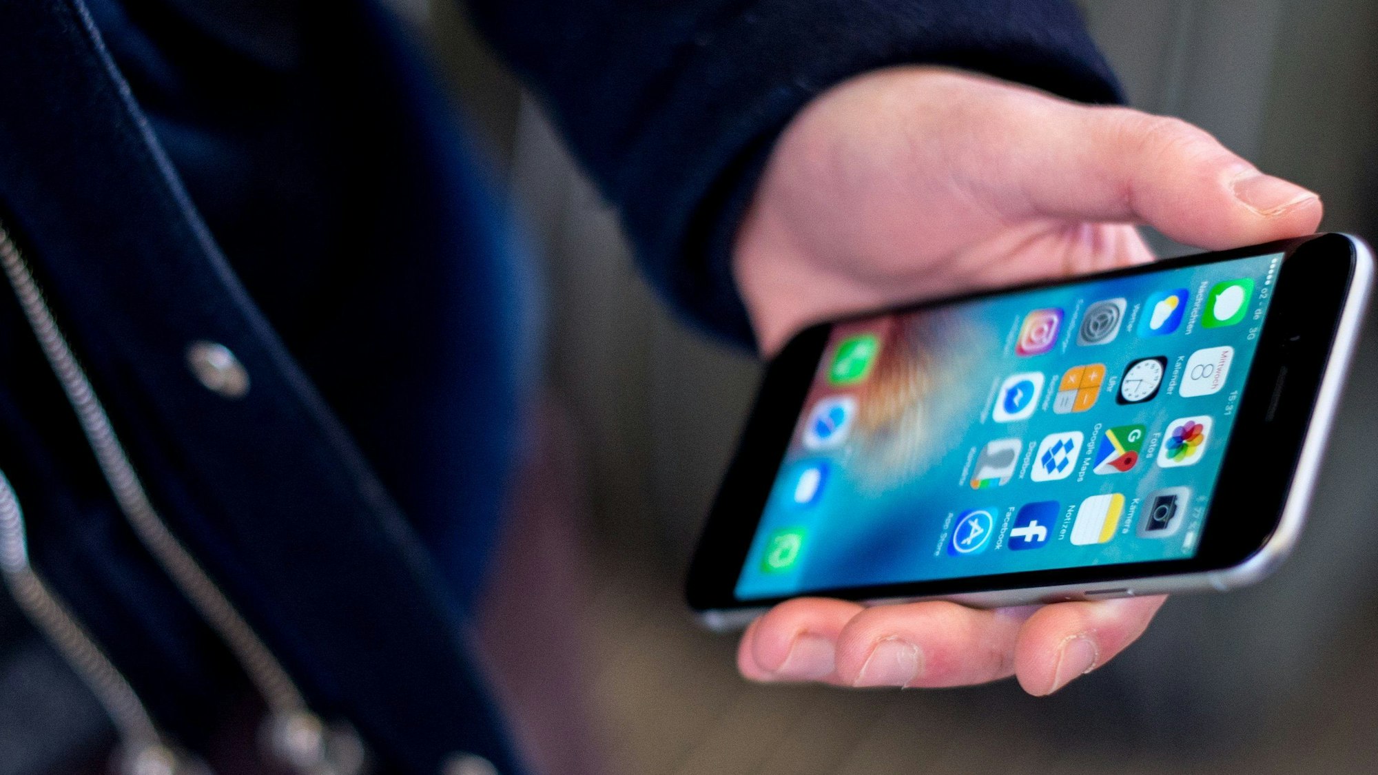 Das Bild zeigt eine Person, die ein Handy in der Hand hält.