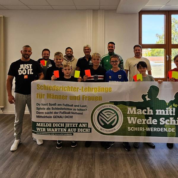 Die elf neuen Schiedsrichter und der Vorsitzende des Schiedsrichterausschuss halten Gelbe und Rote Karten ins Bild und ein Werbebanner für das Schiedsrichterwesen hoch.