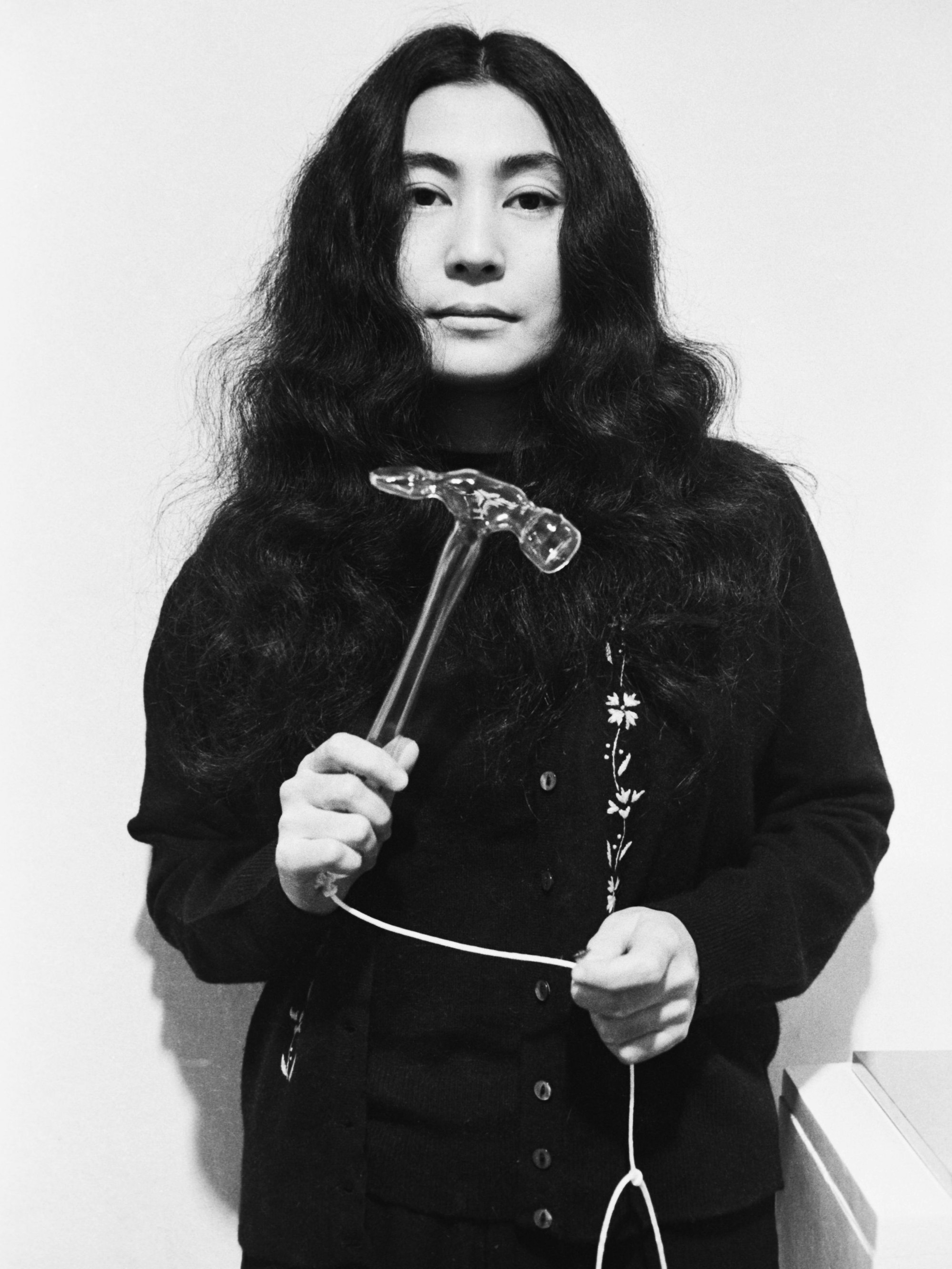 Yoko Ono hält einen gläsernen Hammer in der Hand.