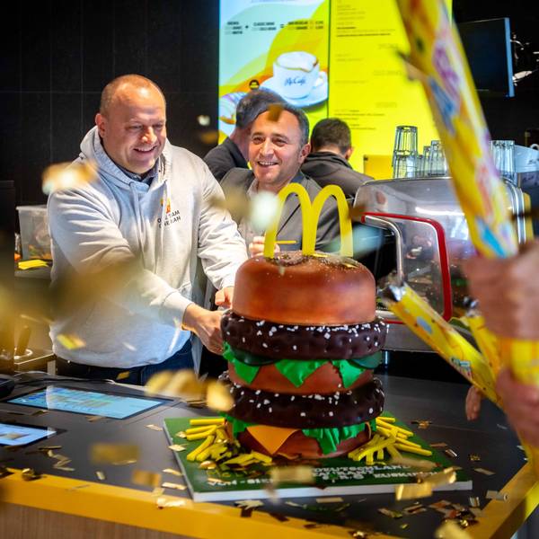 Das Bild zeigt, wie der Restaurant-Leiter und der Operations Manager im McDonald's in Euskirchen eine große BigMac-Torte anschneiden.