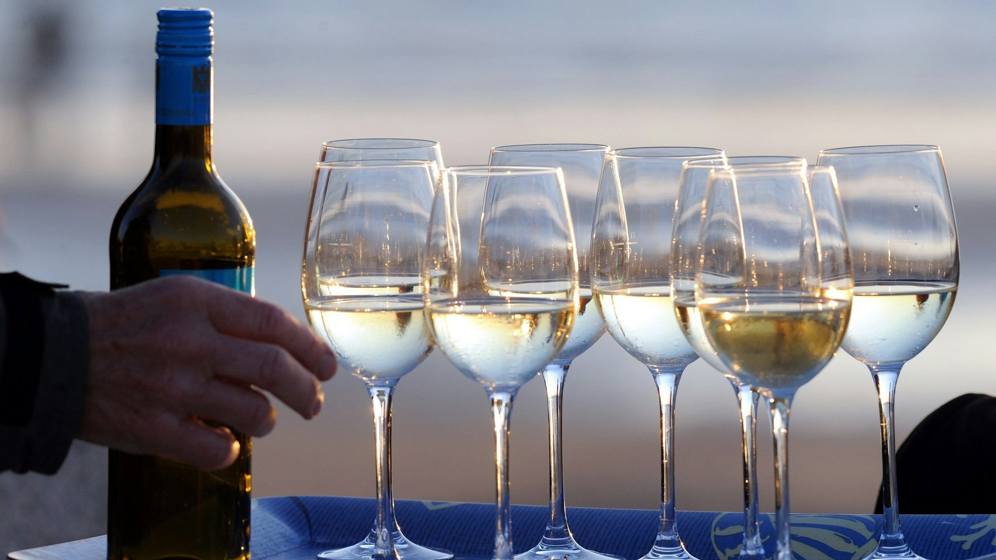 Gefüllte Weingläser stehen im Abendlicht.