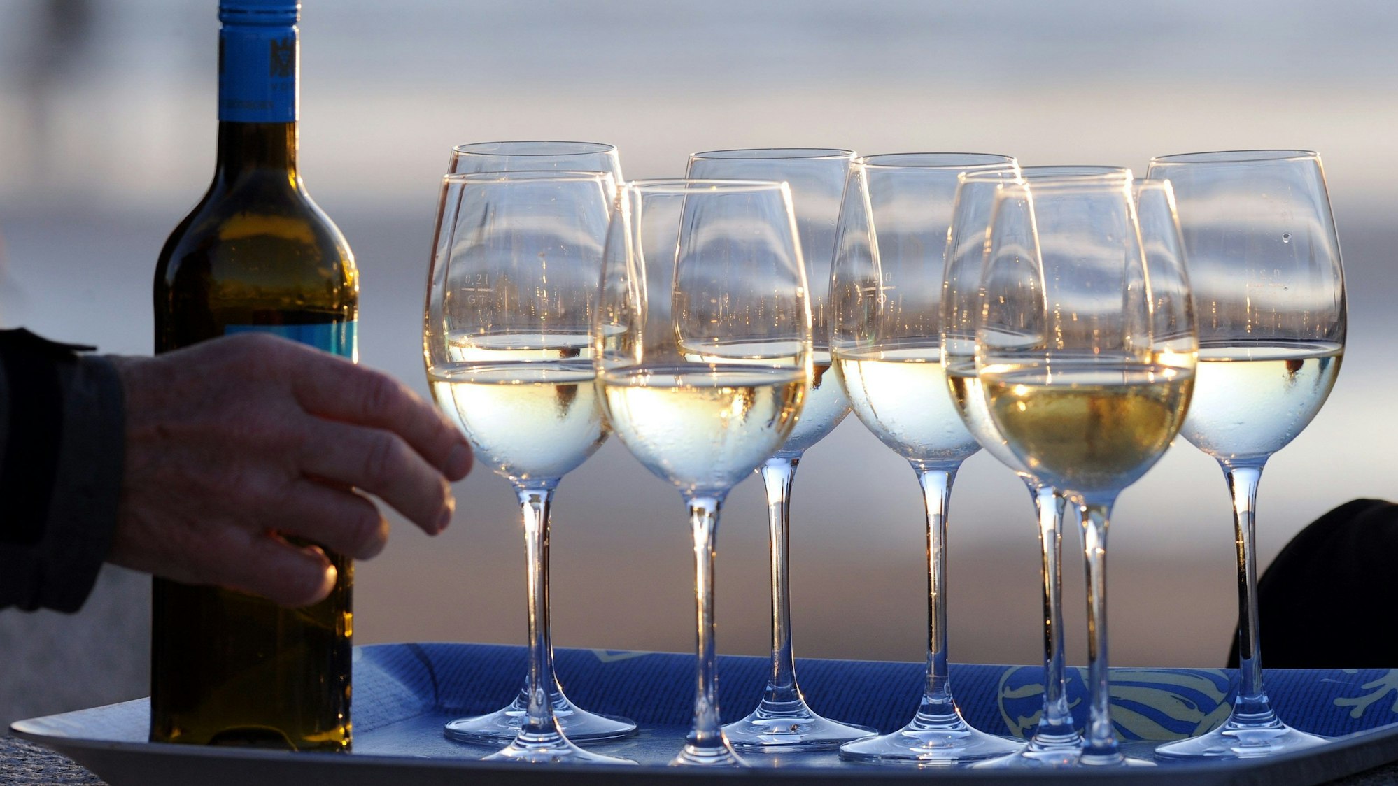 Weingläser und eine Flasche Wein auf einem Tablett.