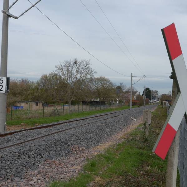Das Bild zeigt eine Eisenbahnstrecke, im Vordergrund hängt ein Andreaskreuz.