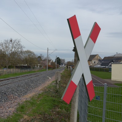 Das Bild zeigt eine Eisenbahnstrecke, im Vordergrund hängt ein Andreaskreuz.