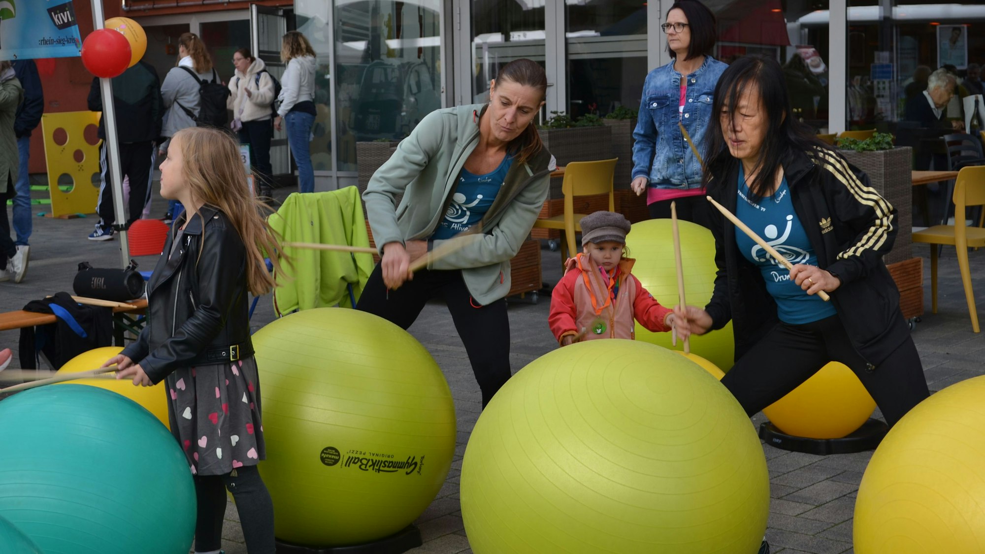 Kinder und Erwachsene trommeln auf Gymnastikbälle ein.